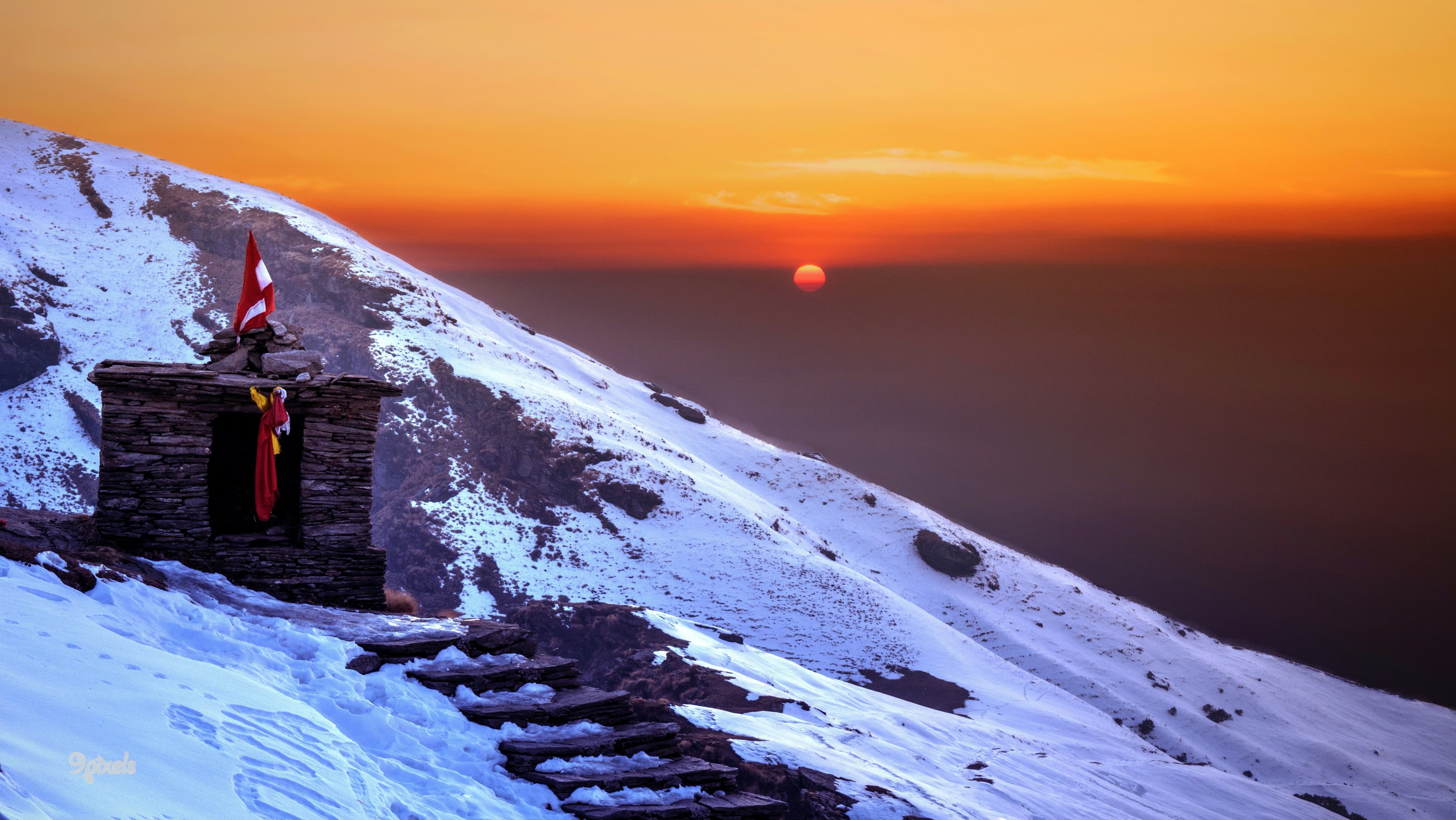 Tungnath Temple on a snow-covered Himalayan summit at sunrise with stone steps along the Chopta trek trail.